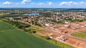 Vista aérea de cidade em expansão com novos bairros e lavouras ao redor